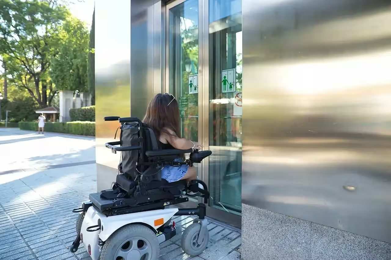 Wheelchair user approaching an accessible elevator at a travel destination